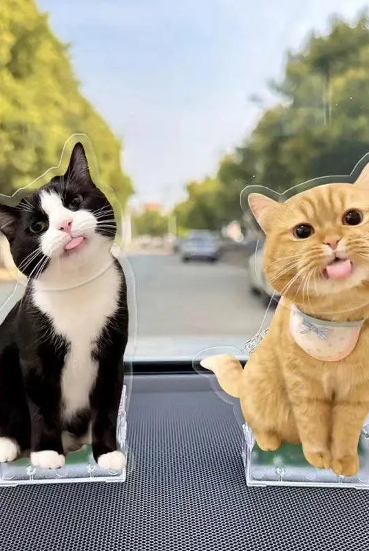 two customized cat bobbleheads standing toghether in the car