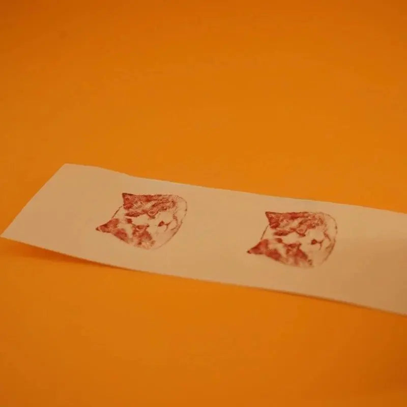 two head prints of a rag doll cat on a piece of paper left by the personalized stamp